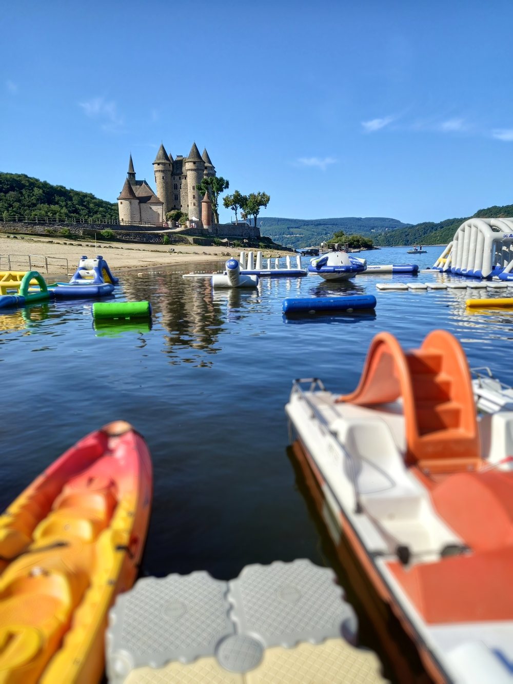 La plage du château de Val, kayaks et pédalos en location au premier plan et structures gonflables sur l'eau