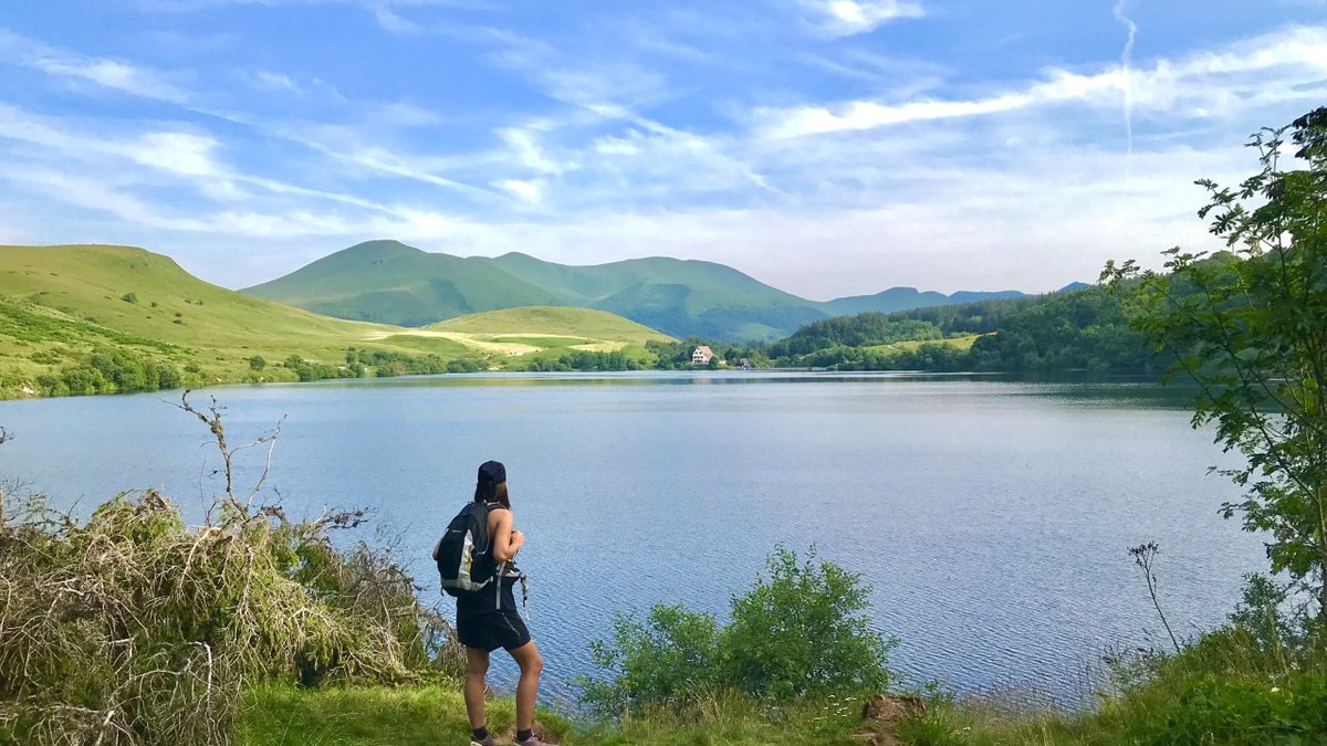 Randonneuse au bord d'un lac de montagne, les monts du Sancy en arrière-plan