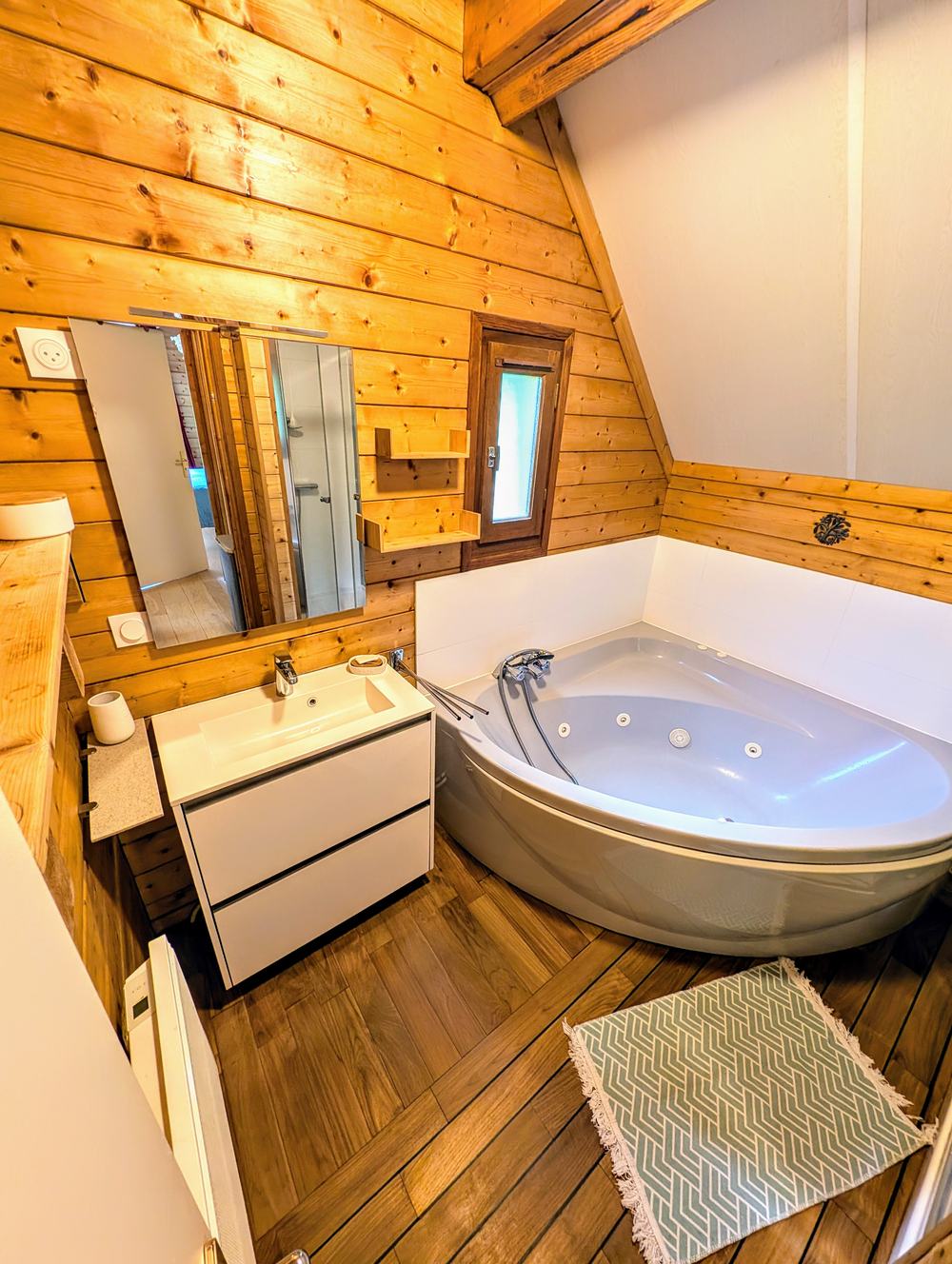 La salle de bain du chalet, baignoire d'angle, vasque et murs en bois
