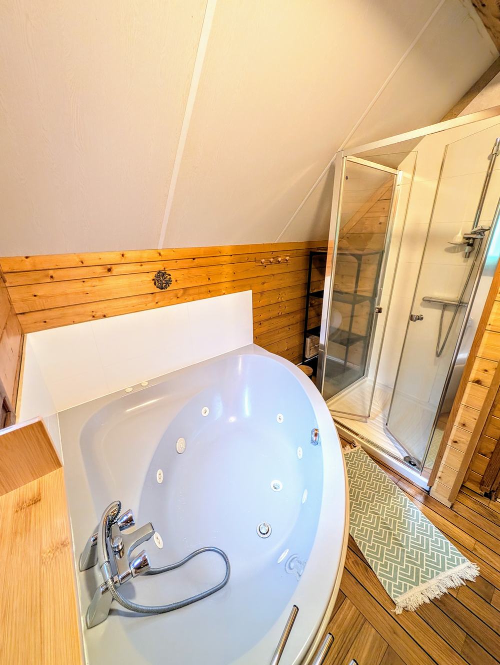 La douche de la salle de bain, à côté de la baignoire d'angle, sous la pente du toit